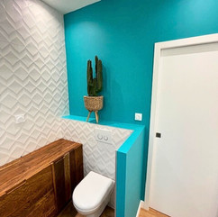 Salle de bain design à Nice avec WC suspendu, meuble bois sur mesure et mur turquoise tendance 2025.