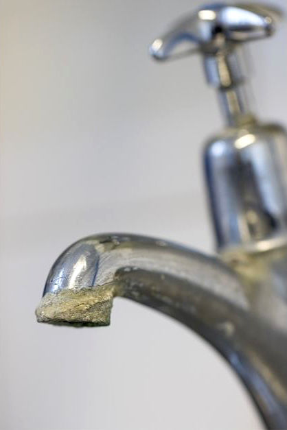 Détail d’un robinet chromé couvert de tartre, montrant l’impact du calcaire sur la robinetterie.