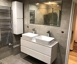 Petite salle de bain rénovée avec meuble suspendu et rangement et douche à l’italienne.