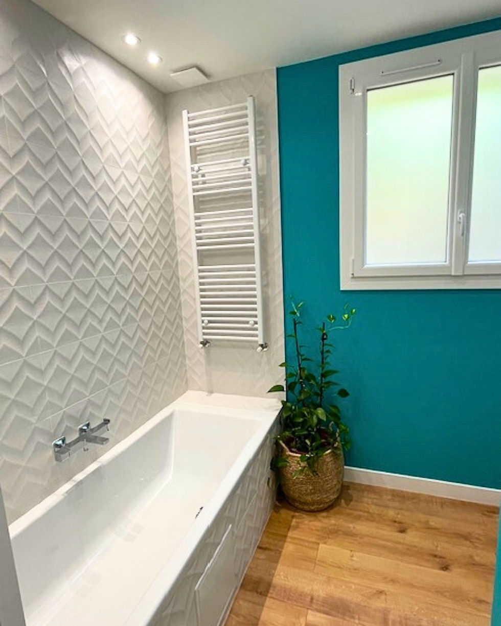 Rénovation salle de bain Nice : baignoire moderne avec carrelage 3D blanc et sèche-serviette vertical.