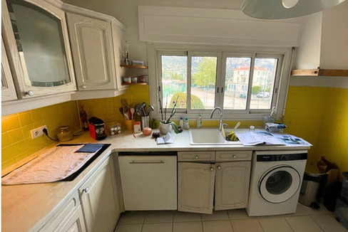 Cuisine ancienne à Nice avec crédence jaune, meubles blancs vieillis et électroménager intégré avant rénovation.