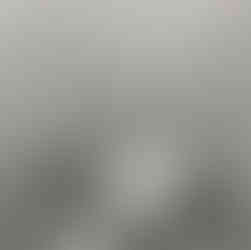 Vue rapprochée d’un WC suspendu rimless avec douchette, poubelle inox et plaque affleurante sur carrelage marbre.