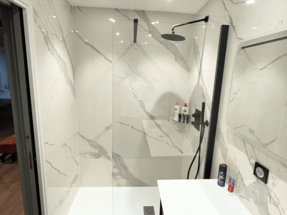 Douche à l’italienne claire avec parois vitrées et carrelage effet marbre blanc.