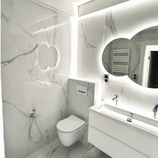 Salle de bain blanche : WC suspendu, meuble vasque, miroir rétro-éclairé et éclairage LED périphérique.