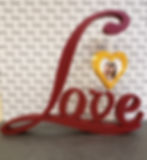 3D printed decoration of the word "Love" in script with a gold heart hanging from the top of the L that can hold a picture.