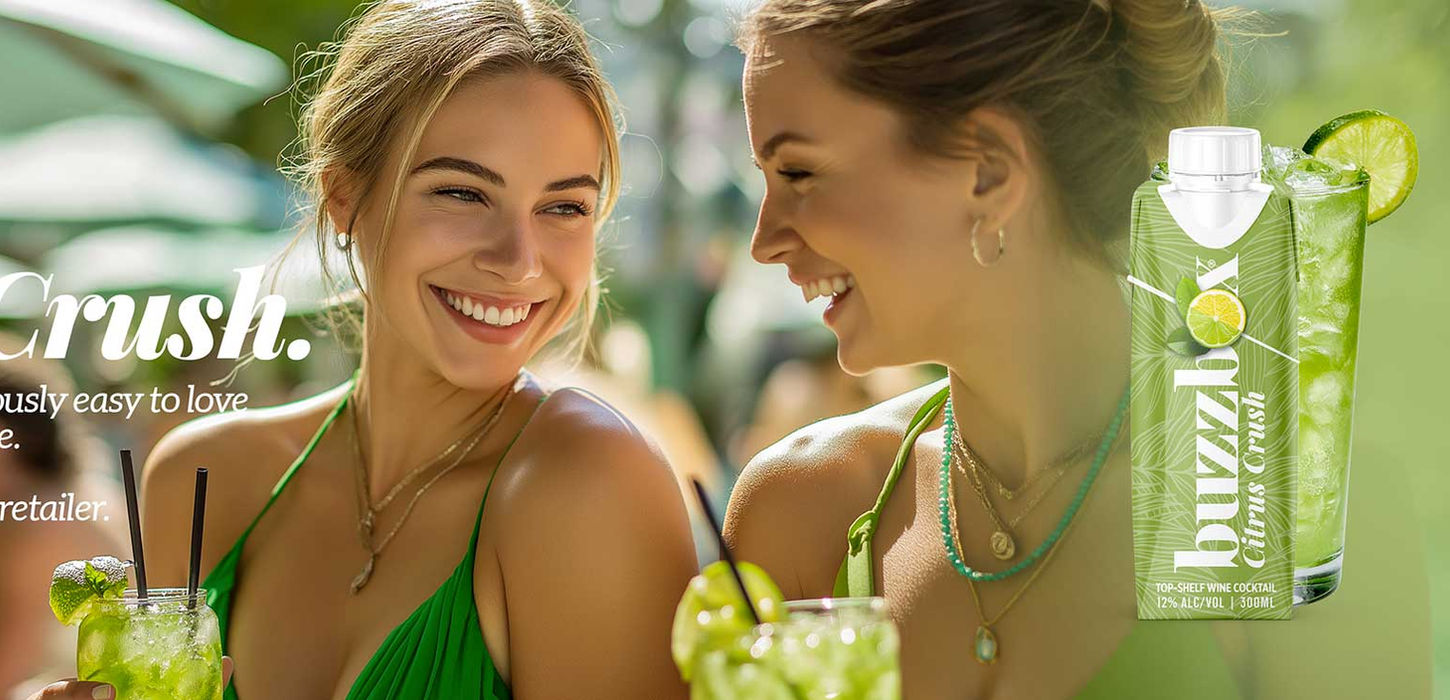 Two women enjoying crush drinks on the beach under green umbrellas