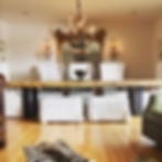 Heavy wooden dinner table in front of ornate mirror and chandeliers