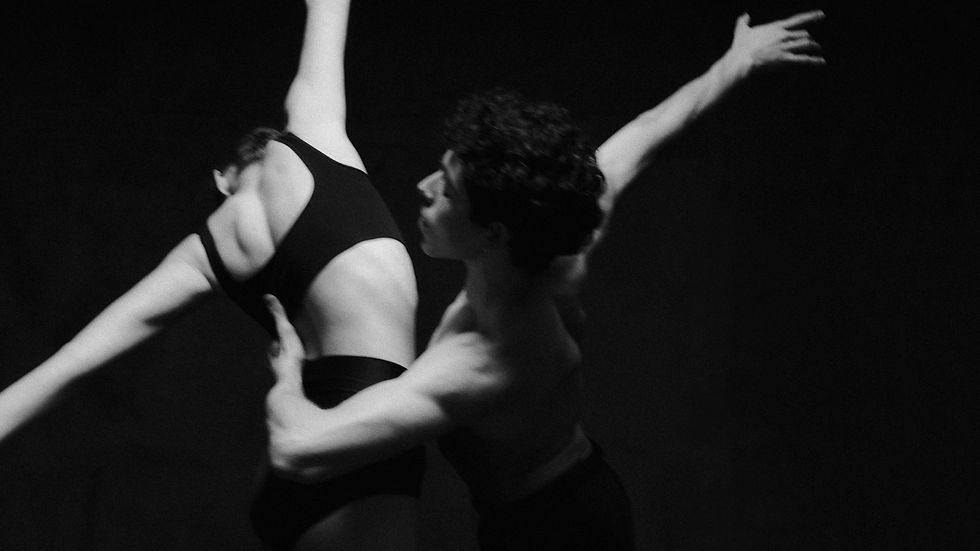 Two ballet dancers performing against a dark background