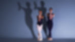 Two dancers casting hand shadows against the wall.