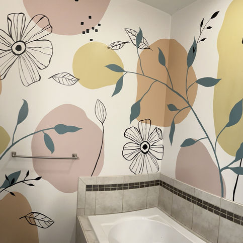 A mural in a residential bathroom featuring black flowers, green leaves, and pink, orange, and yellow circles. 