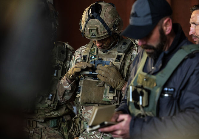 Professional defence photography of British soldier on ATAK (Android Tactical Assault Kit) or an End-User Device (EUD)