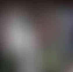 Un perchero con varias prendas de ropa incluyendo camisetas, blusas y pantalones. Se pueden ver distintos estilos como camisetas blancas, una prenda de cuadros escoceses rojos, y varios tonos de azul denim. Las prendas están colgadas en perchas metálicas con cintas rosas.