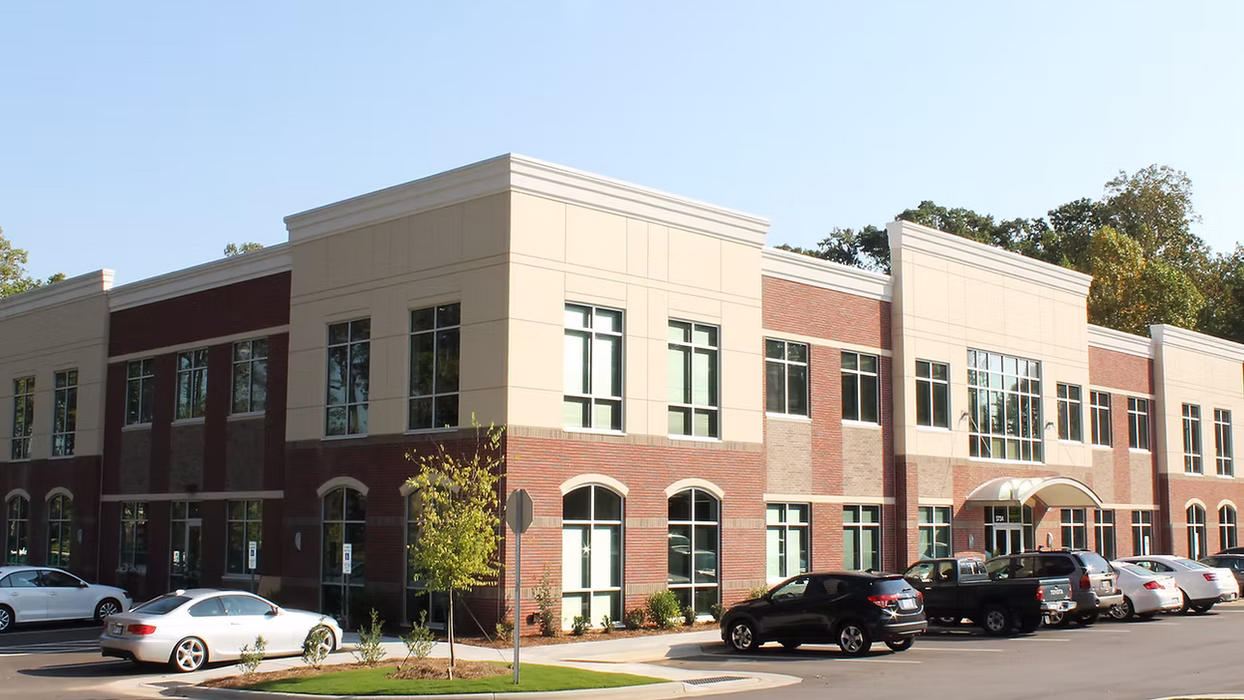 Trinity Ridge Office Park exterior with two-story brick office building, large windows, parking area, and landscaped grounds