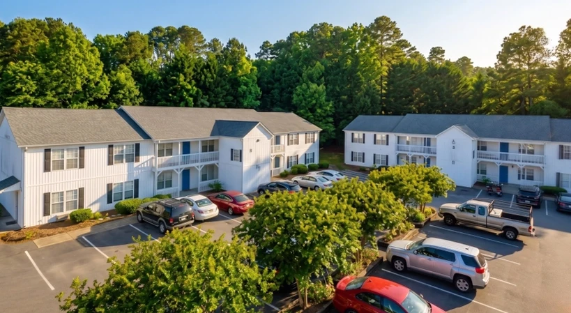 Edgewood Apartments aerial exterior view with white apartment buildings, parking lot, landscaped grounds, and mature trees