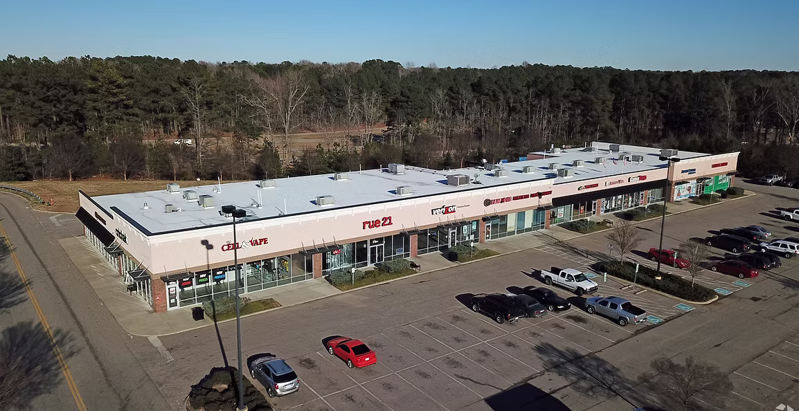 Zebulon Crossing Shopping Center aerial view with retail storefronts, parking lot, major tenants, and wooded surroundings