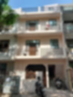 Three-story beige building with balconies. The Property By Shiva Associates.