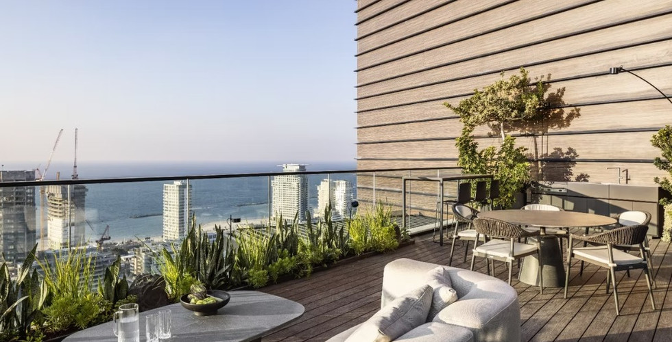גינת גג עם דק עץ, פינת ישיבה ופינת אוכל, צמחייה לאורך המעקה ונוף פתוח לים ולמגדלים עירוניים