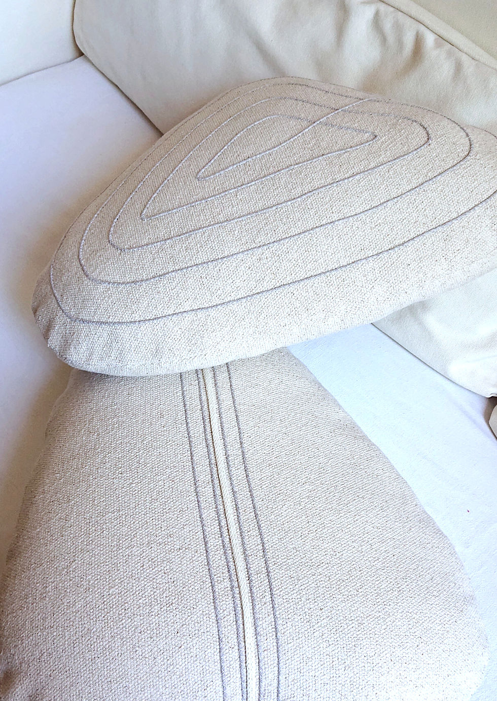 CAOU coussin forme galet en coton très brut écru, présenté avec un modèle coordonné.