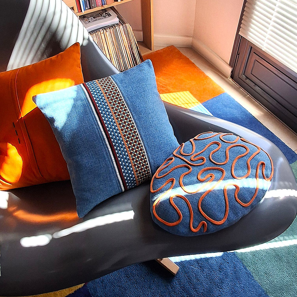 Coussins bleus et orange sur un canapé noir, Coupé Cousu Gàli Coussin Créateur.