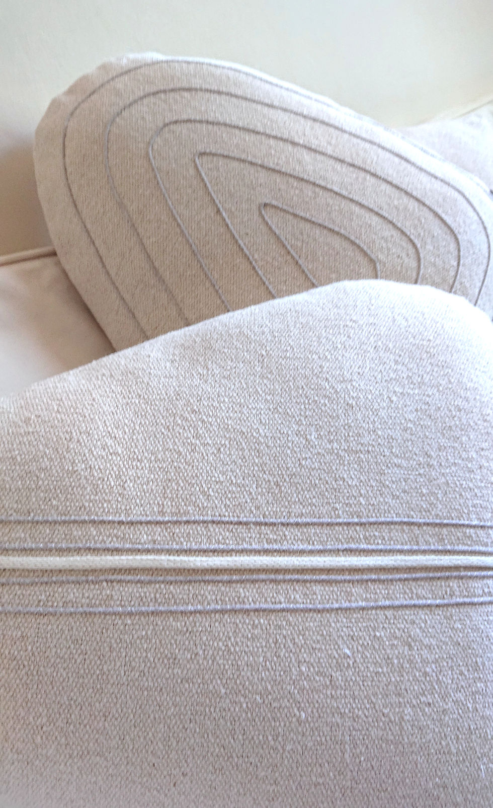 CAOU coussin forme galet en coton très brut écru, présenté avec un modèle coordonné.