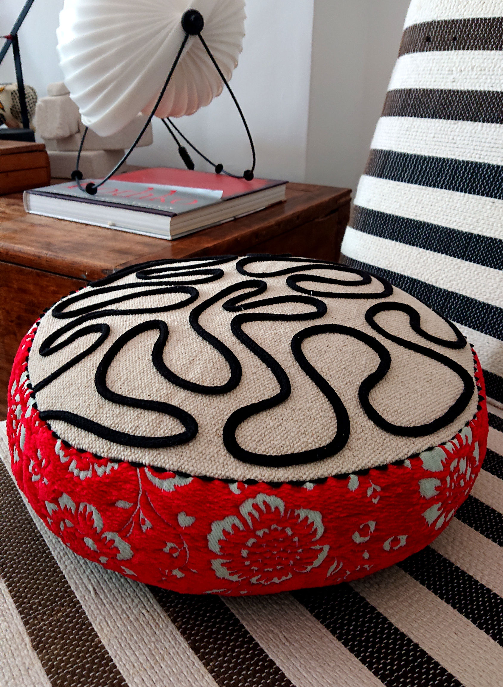 Zàro coussin ARTY, rond, en coton très brut, jacquard et cordon de coton, photographié sur un fauteuil rayé.