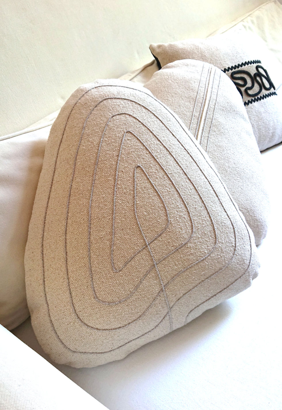 CALC coussin forme galet en coton brut écru, présenté avec un autre modèle