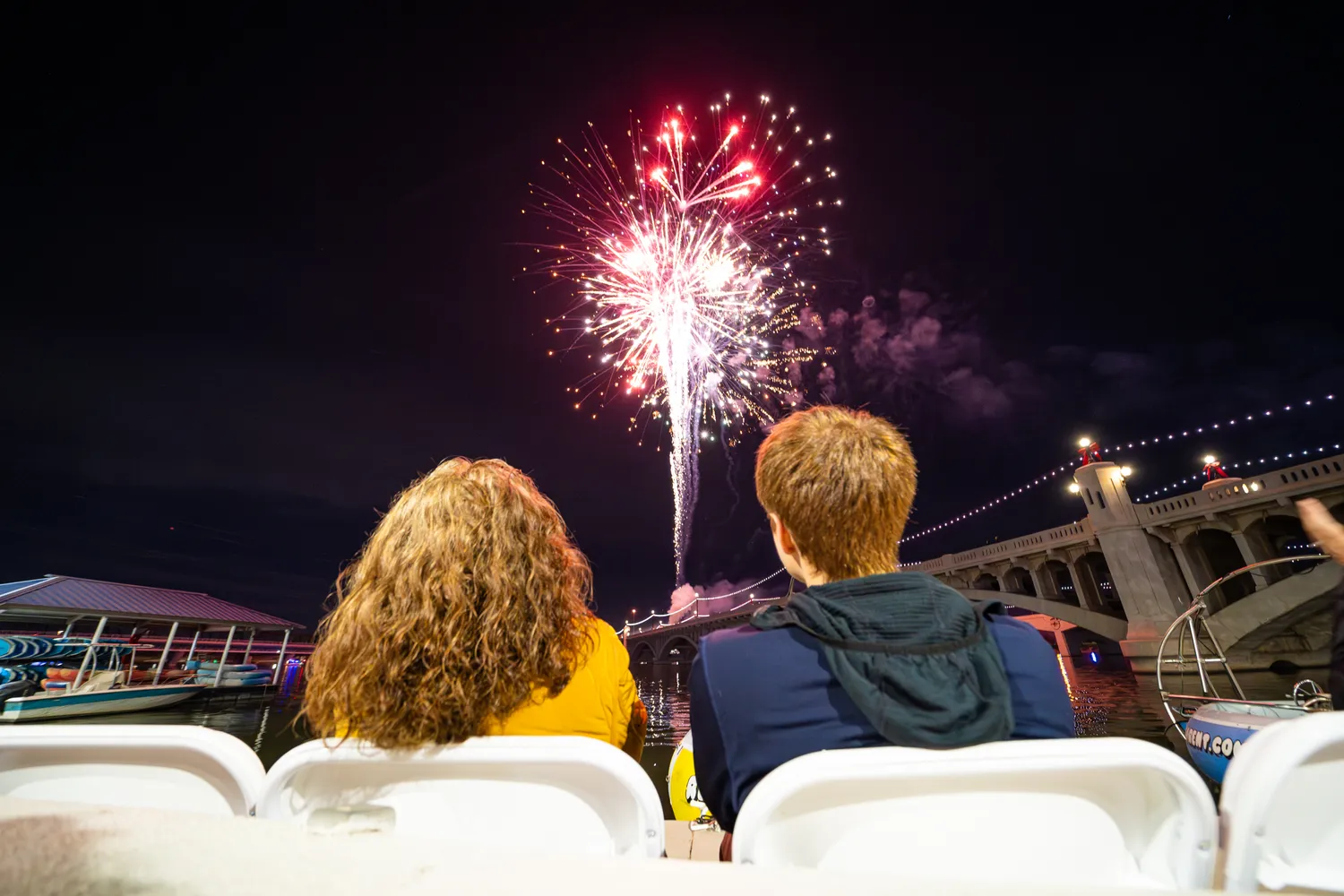 Fireworks lighting patterned colors over Tempe Town Lake evening sky