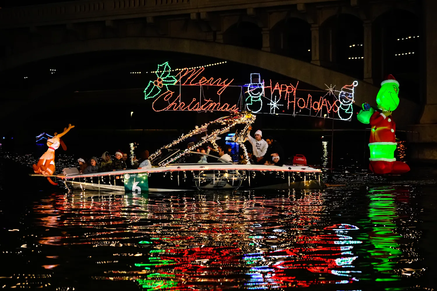 Holiday lighted boats reflecting on calm water at Tempe Town Lake at night