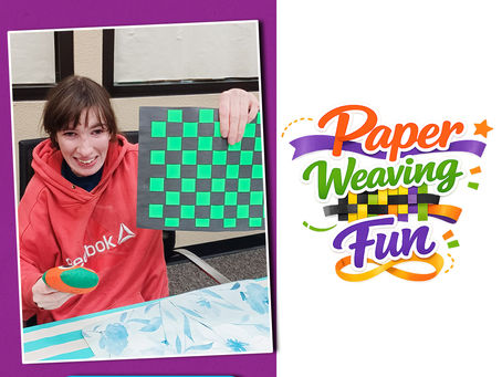 Member proudly holding completed paper weaving craft project