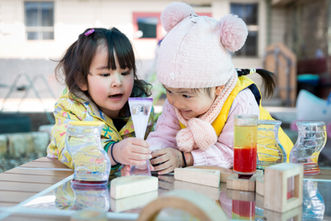 Two young girls outside playing with toys at a daycare