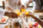Close up of several hands making a toast with glasses of orange juice at a restaurant