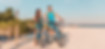 Young couple riding bikes at the beach with Sanibel Lighthouse and people sunbathing in the background