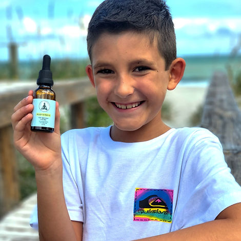 Photo of child holding CBD tincture in hand, on a dock by the beach