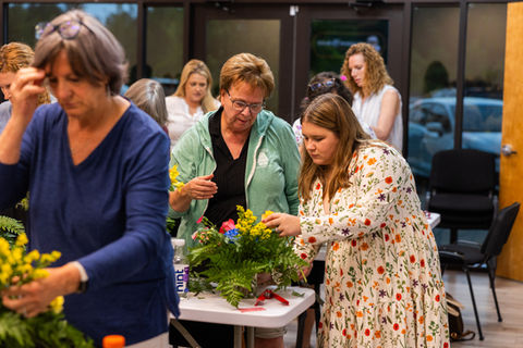 Instructor guiding students in a flower arranging class, showcasing tips and techniques for creating beautiful floral designs.