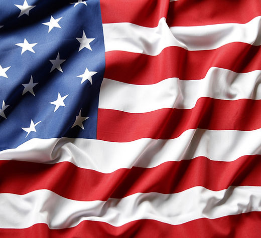 American flag billowing in the wind, featuring bold red and white stripes and a field of white stars on blue.