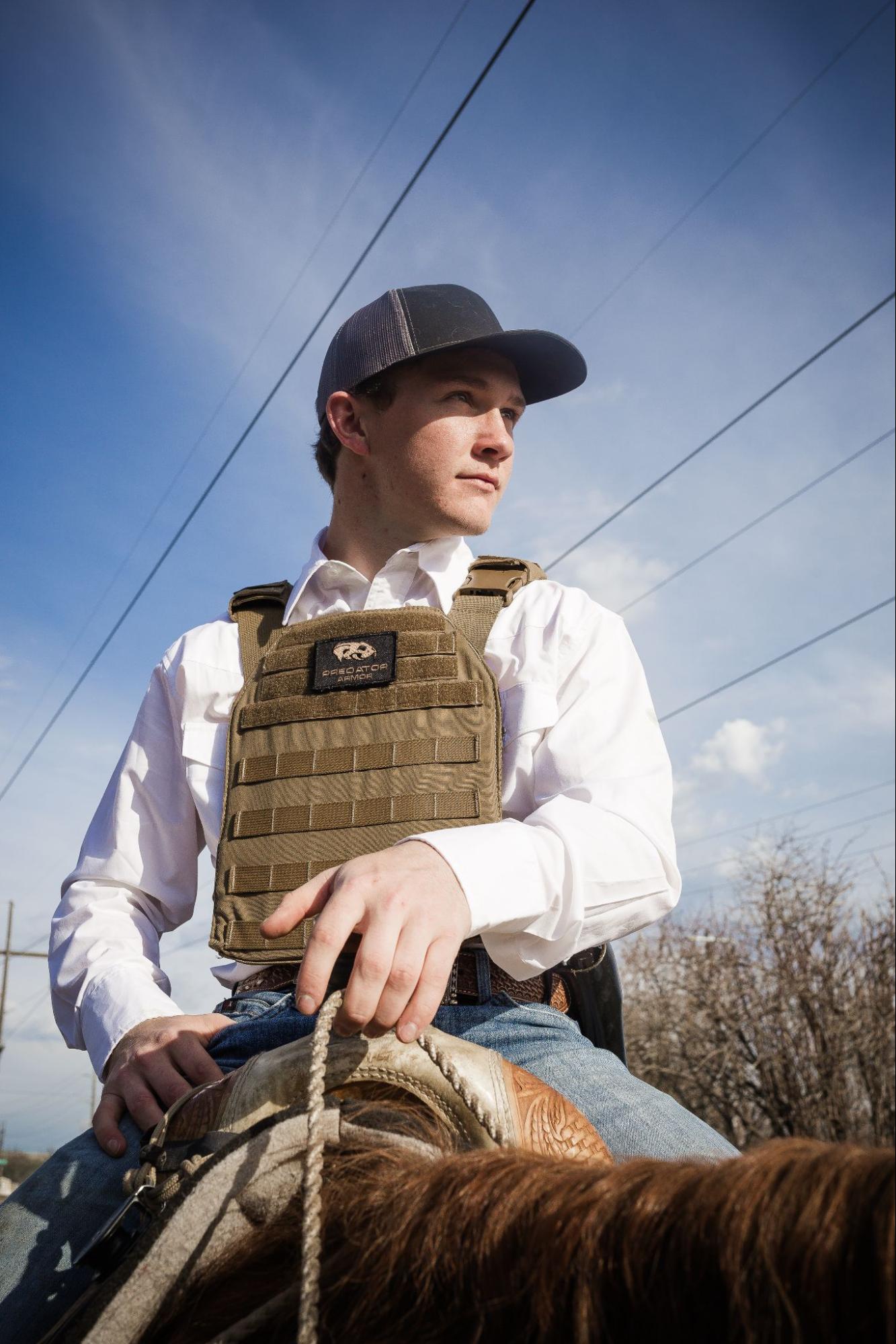 Photo of a man riding a horse wearing body armor. Predator Armor Plate Carrier in Coyote Tan. 