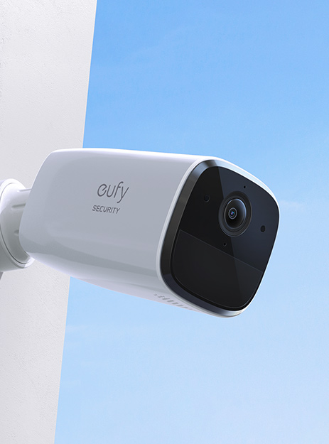 White security camera with "eufy Security" text mounted against a blue sky backdrop. Sleek, modern design, conveys security and vigilance.