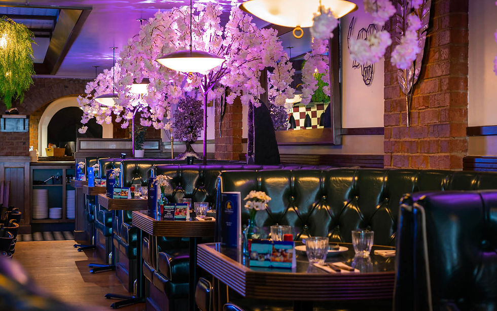 Inside Los Pampas Brazilian Steakhouse Halifax showing luxury booths, cherry blossom trees, and open kitchen grill area