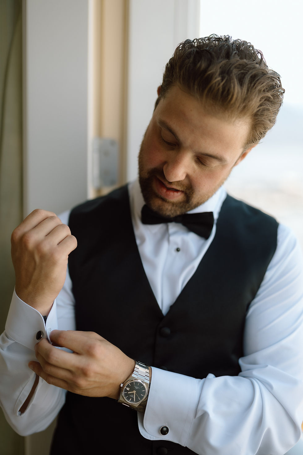 Groom adjusting suit jacket before waterfront wedding ceremony at OkanGroom adjusting suit jacket before waterfront wedding ceremony at Okanagan Lake in Kelowna.agan Lake in Kelowna.