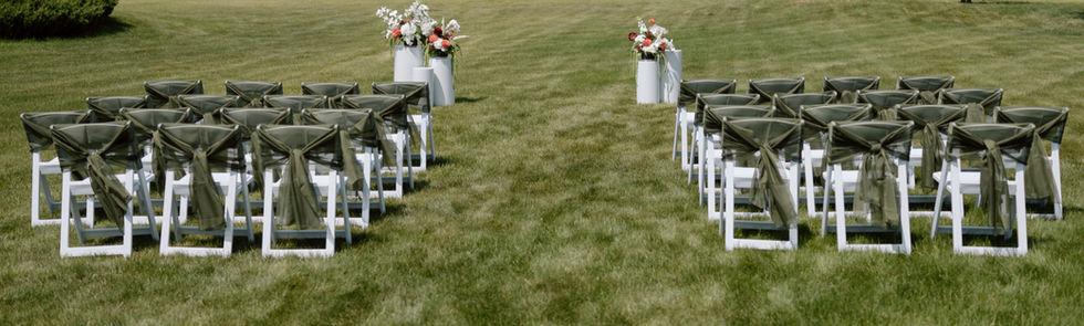 White folding chairs styled with olive green chair covers for an elegant outdoor wedding ceremony in Lloydminster.
