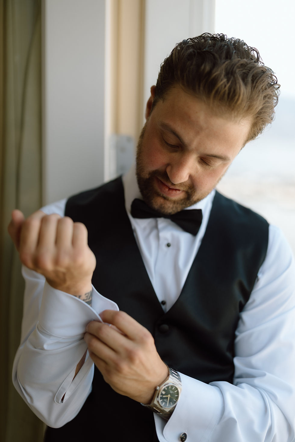 Groom adjusting suit jacket before waterfront wedding ceremony at Okanagan Lake in Kelowna.