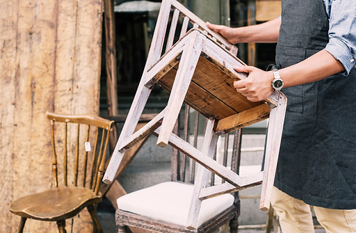Man holding chair while standing against store