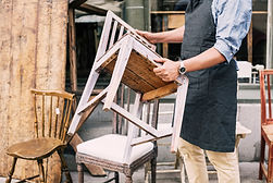 Midsection of man holding chair while standing against store