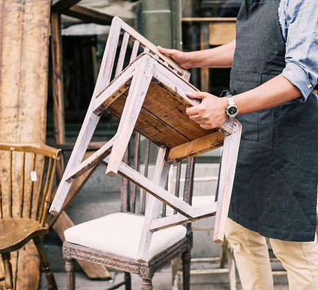 Midsection of man holding chair while standing against store