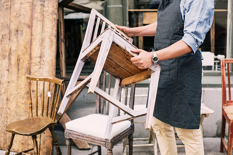 Midsection of man holding chair while standing against store