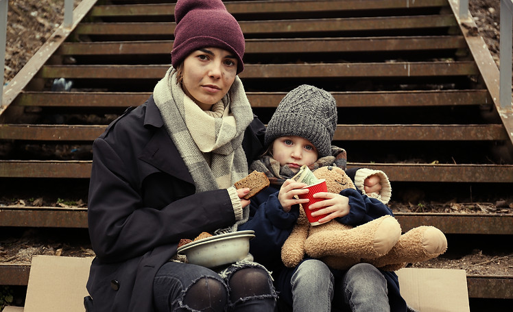 Poor mother and daughter with bread sitting on stairs outdoors.jpg