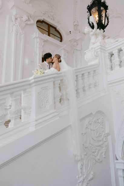 Romantic portrait of a bride and groom kissing on the grand staircase inside Belvedere Palace