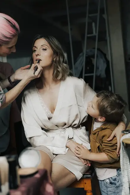 bride with son while having her make-up put on