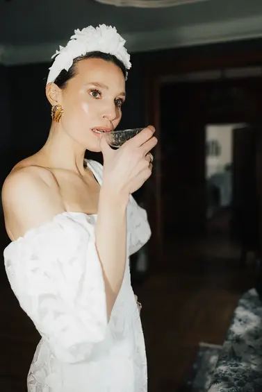 beautiful bride in Dior dress is drinking from a glass of champagne