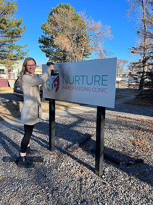 Woman painting the sign for Nurture Family Feeding Clinic, emphasizing support for postpartum wellness and feeding.